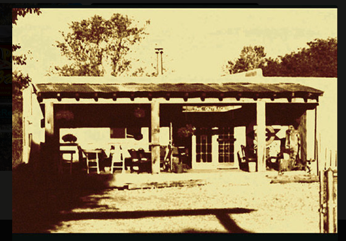 The original Out Back building in Taos, with its wooden porch and hand-painted sign