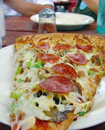 Loaded slice of pizza on a sesame-seed crust at Taos Pizza Out Back