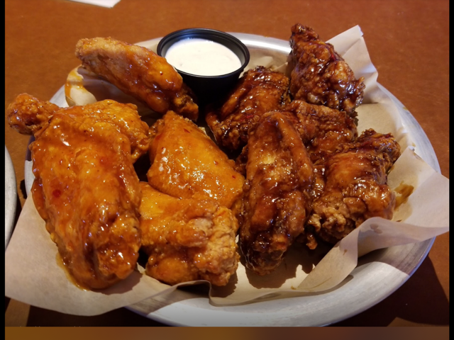 Basket of buffalo wings tossed in hot and BBQ sauce with a cup of ranch