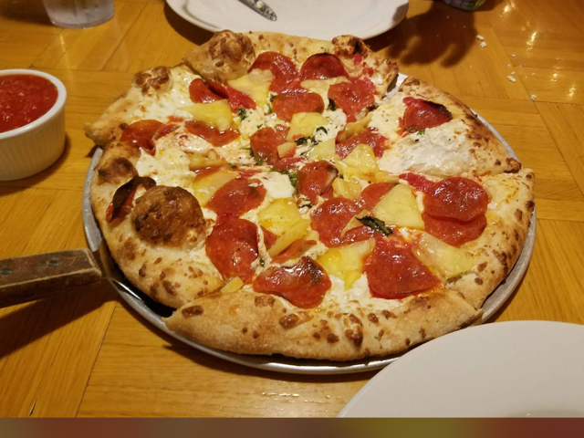 Pepperoni and pineapple pizza with ricotta and basil on a metal pan