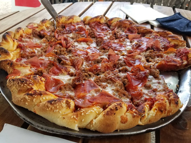 Meat lovers pizza with pepperoni, sausage and ham on the sesame crust, out on the patio