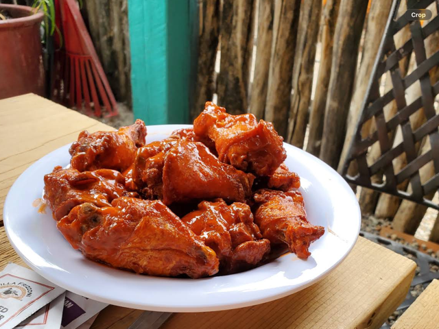 Plate of saucy buffalo wings on a patio table by the coyote fence
